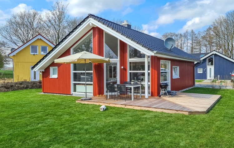 Ein rotes Ferienhaus mit Terasse, umgeben von Rasen.